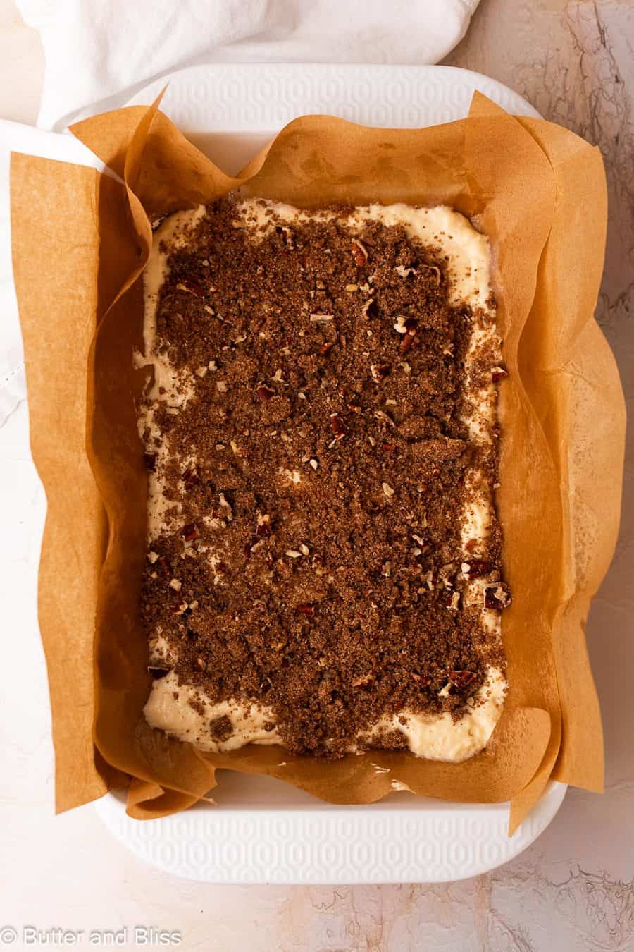 First layer of buttery streusel on coffee cake batter in a 9x13 baking dish.