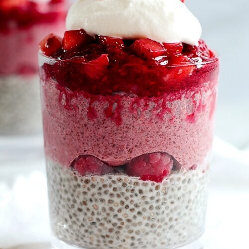 Glass of red berry chia pudding topped with whipped cream