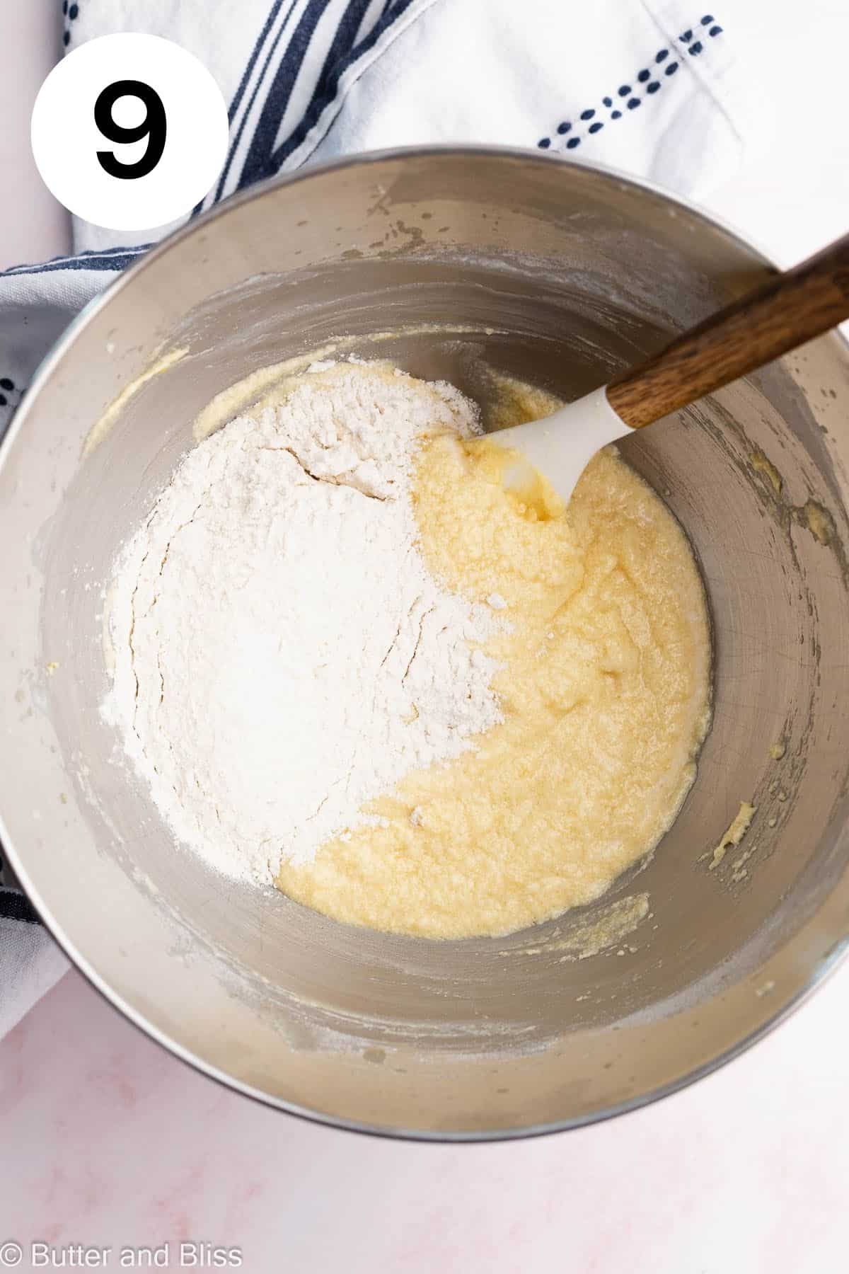 The last addition of flour being added to a cake batter in a mixing bowl.