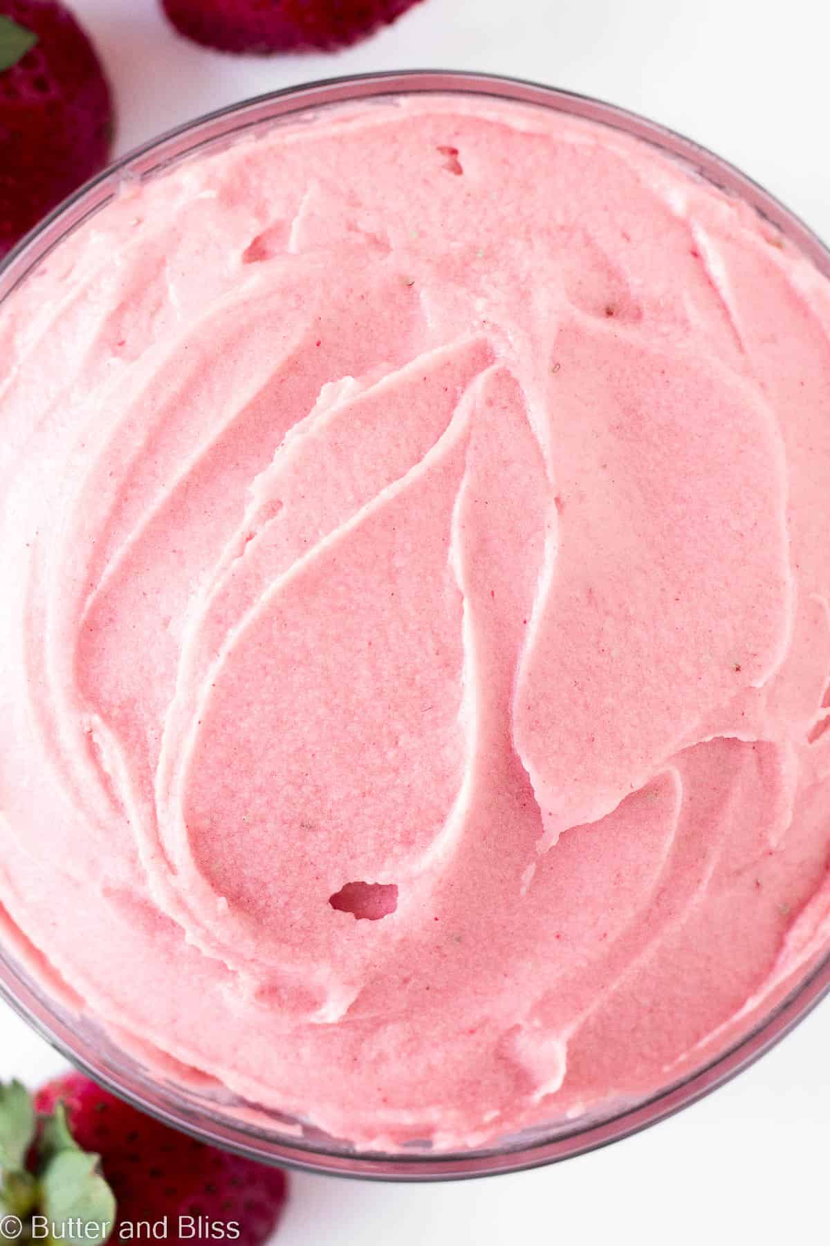 Close up on a bowl of whipped strawberry buttercream frosting.