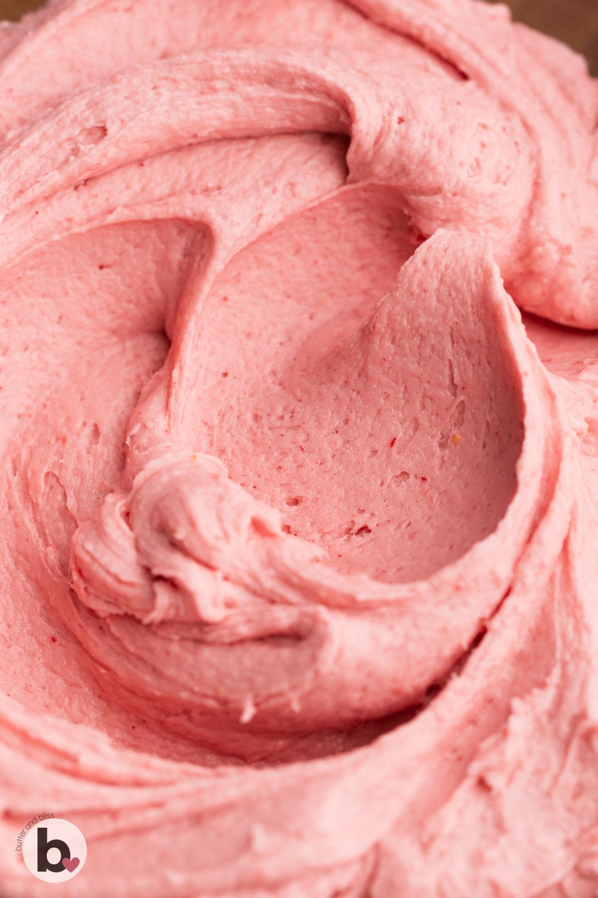Creamy strawberry buttercream frosting in a bowl.