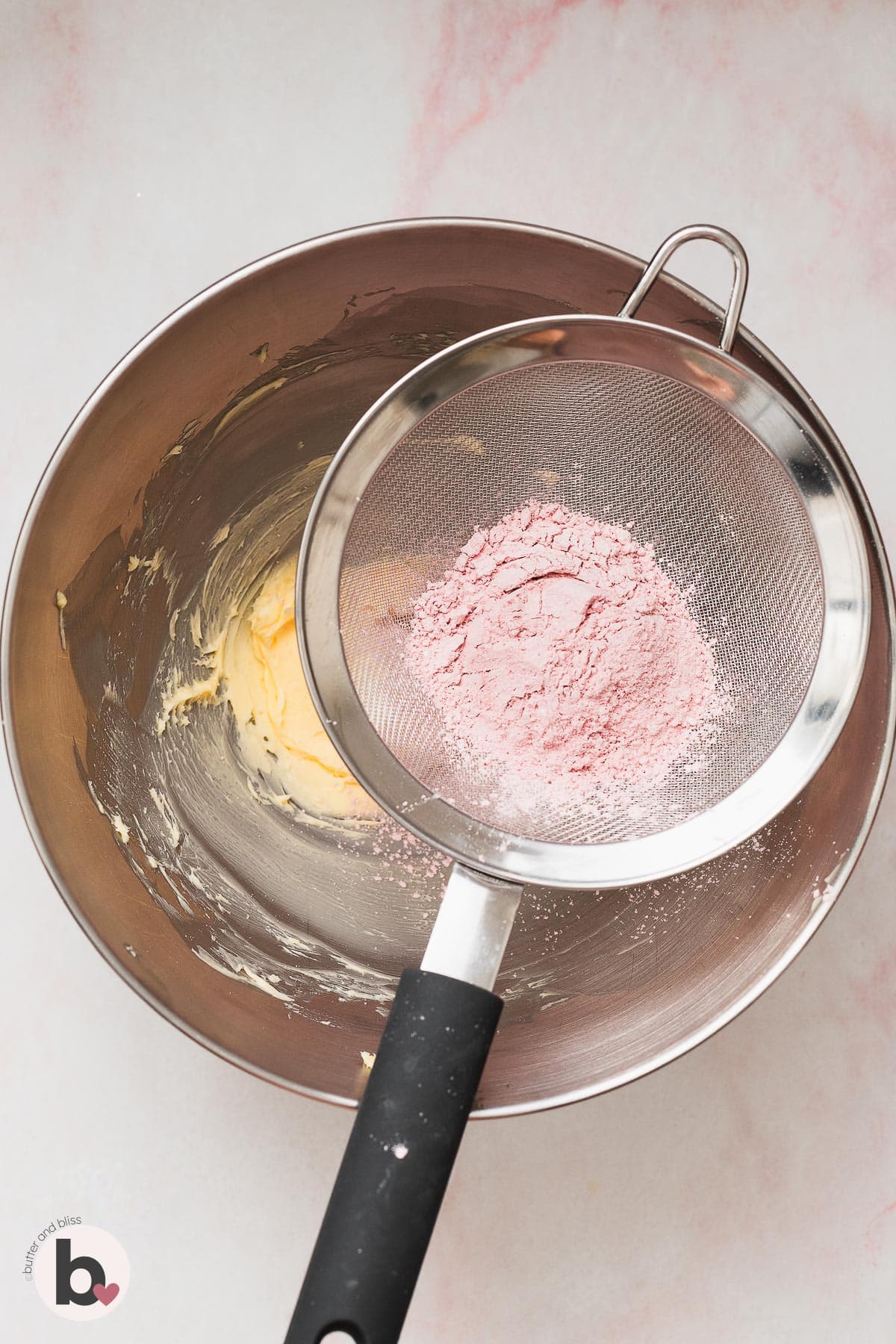 Freeze dried strawberry powder sifted over a bowl of creamed butter.