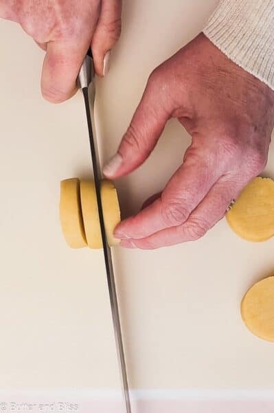 Hand cutting slice-and-bake lemon shortbread cookies.