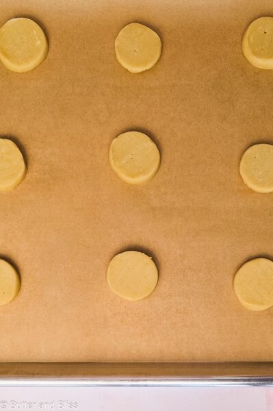 Shortbread dough rounds on a baking sheet.