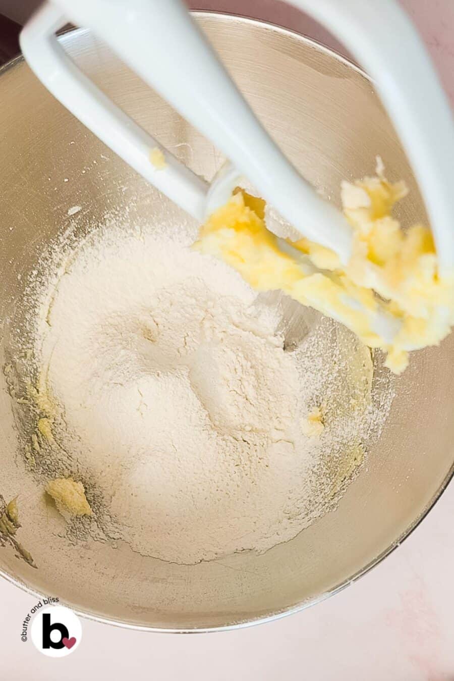 Dry ingredients added to creamed butter in a mixing bowl.
