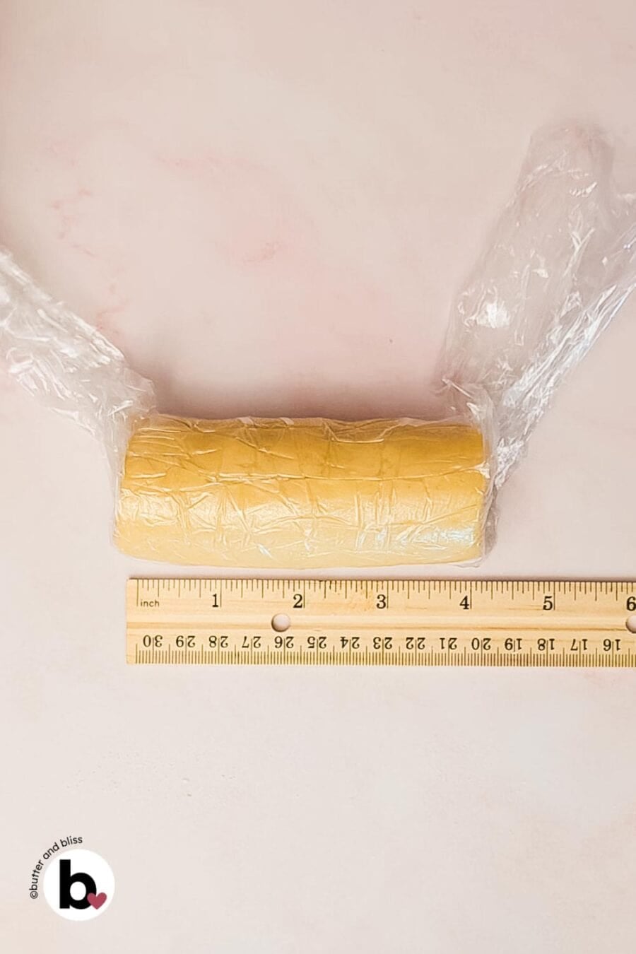 Lemon shortbread dough rolled into a log and wrapped with plastic wrap.