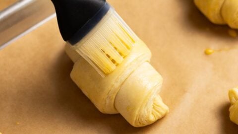 Proofed croissant getting brushed with egg wash.