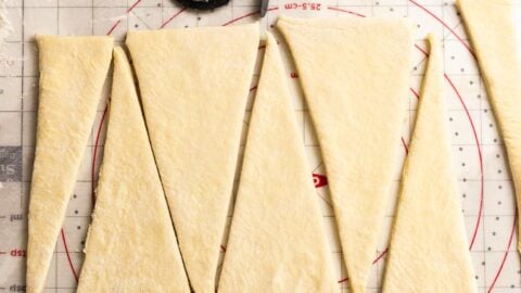 Croissant dough cut into triangles with a pizza cutter.