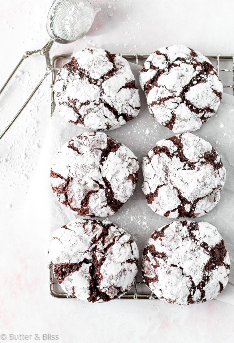 A small batch of holiday cookies arranged on a wire cooling rack with a powdered sugar dusting.