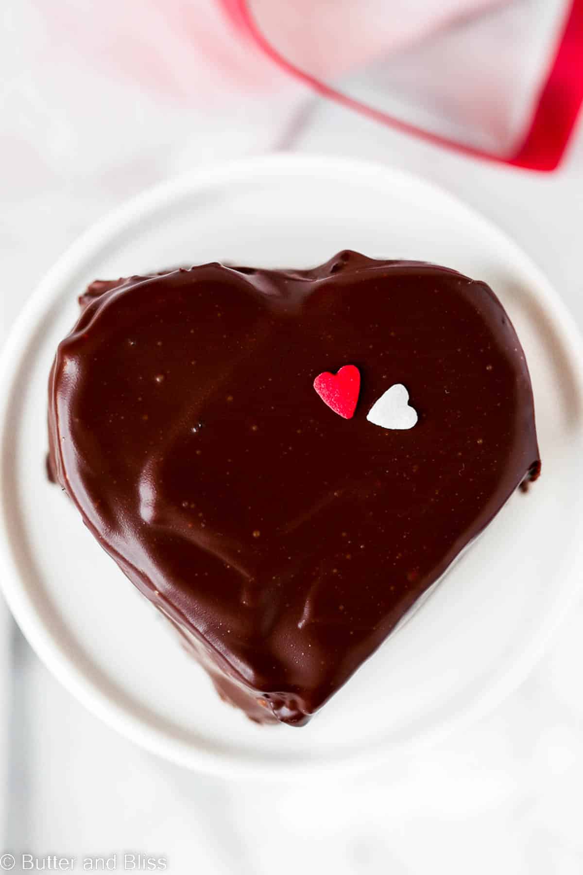 Single heart shaped chocolate coated mini cake set on a mini cupcake stand.