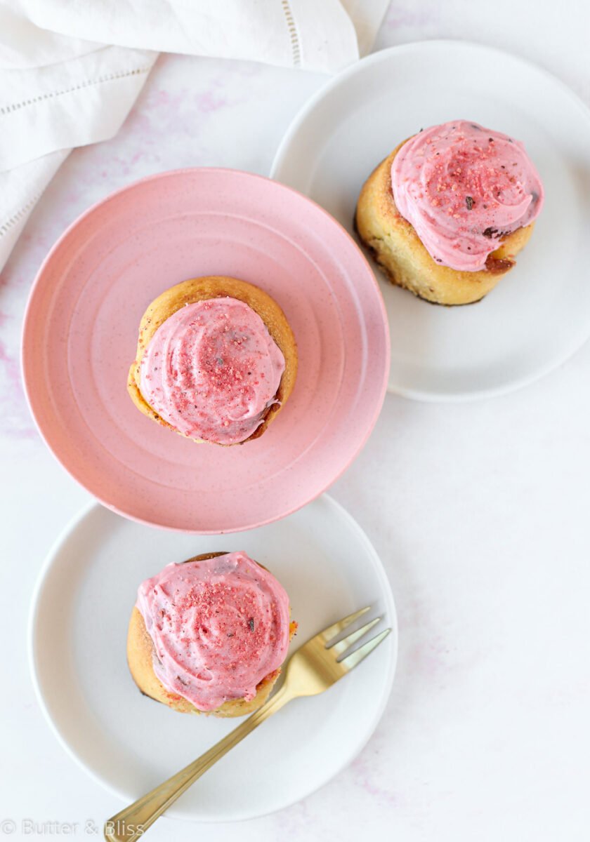 Frosted strawberry cinnamon rolls on plates