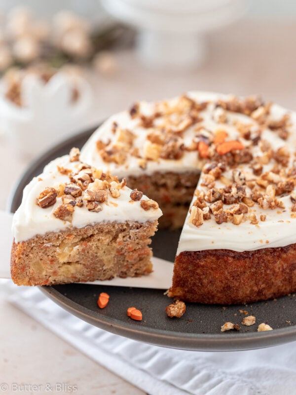 Frosted carrot cake with a slice cut on a platter