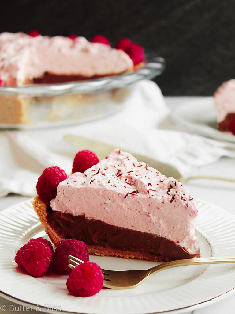 A slice of chocolate cream pie with raspberry topping on a plate