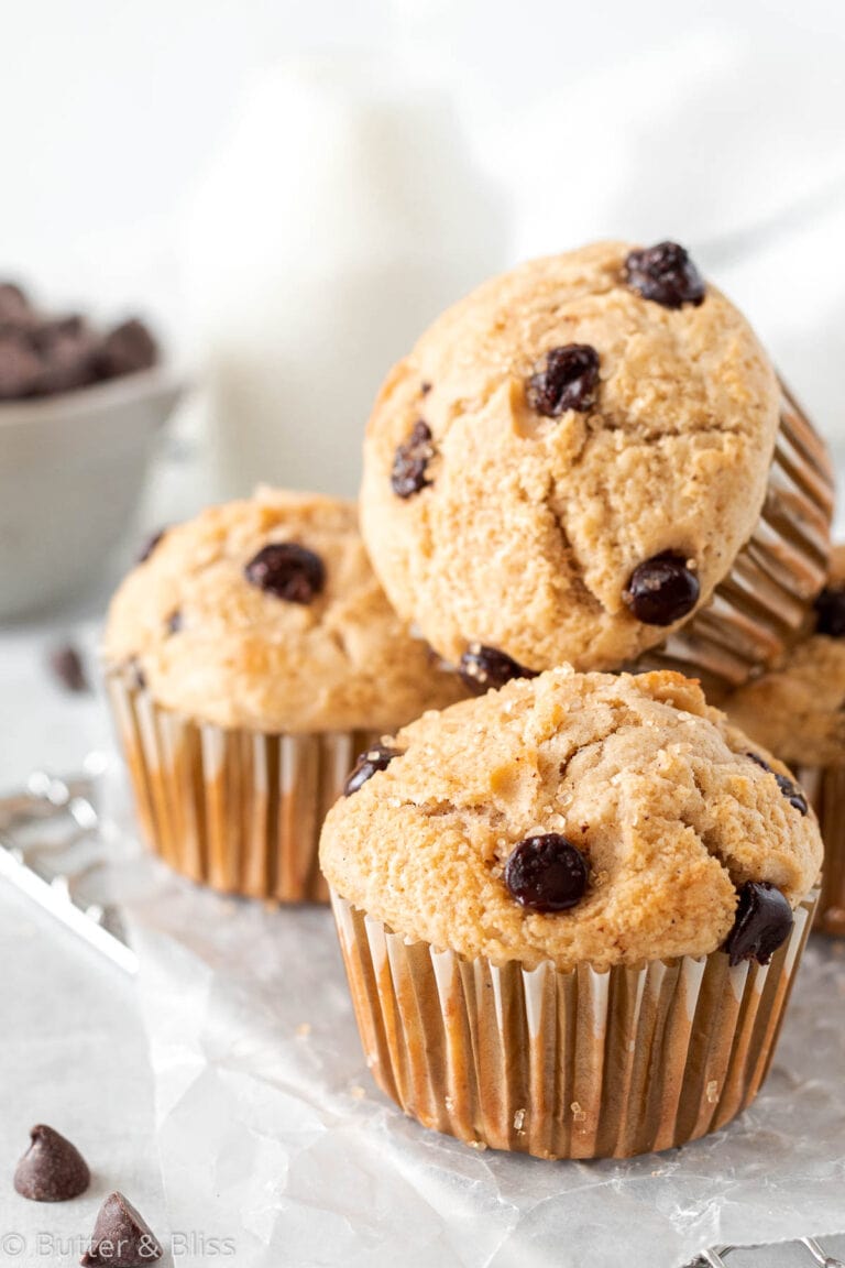 A small batch of chocolate chip muffins stacked on eachother on a wire rack.