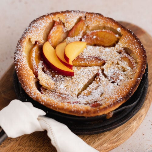 Peach clafoutis in mini cast iron skillet with powdered sugar