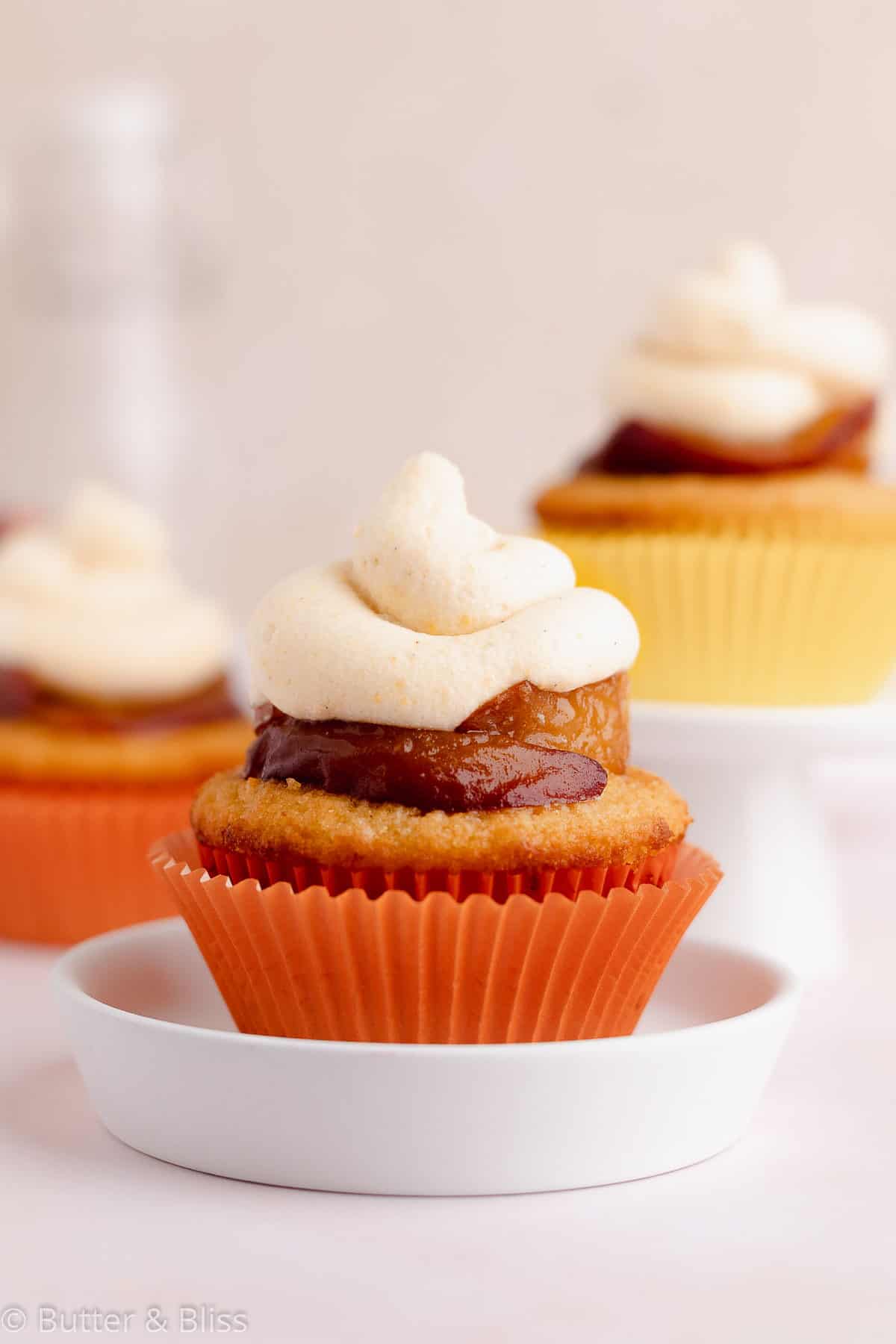 Single peach cupcake with peach frosting and caramelized peaches