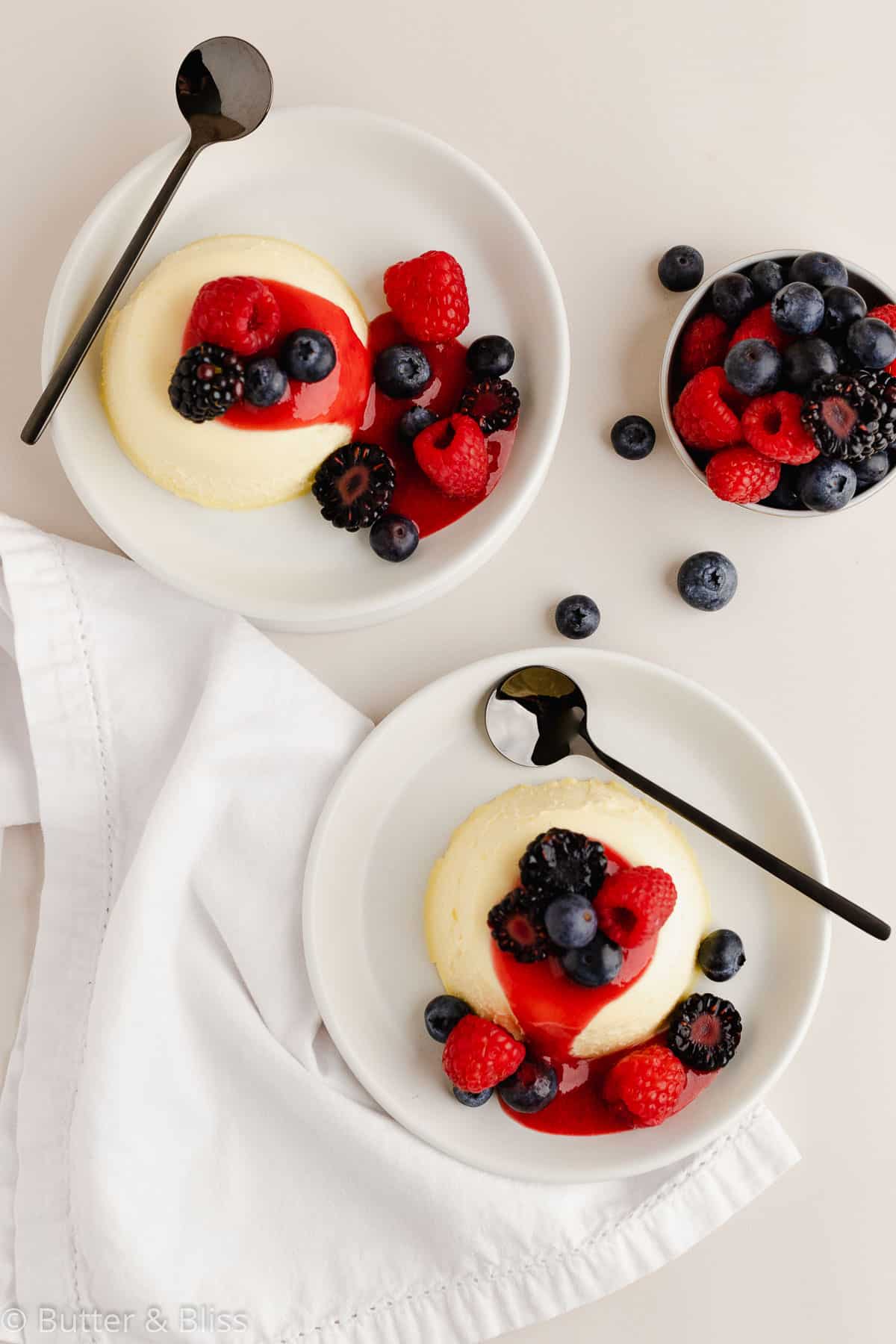 Two servings of corn panna cotta for end of summer labor day desserts on plates with berry sauce