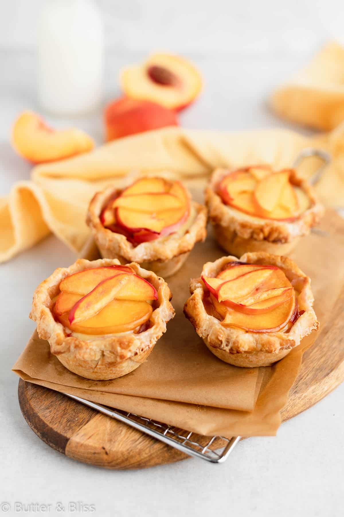 Fresh mini peaches and cream pies on a wooden platter