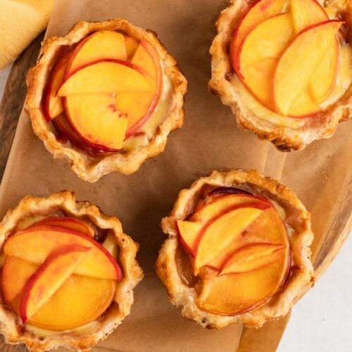 Four mini peaches and cream pies on a wire cooling rack.