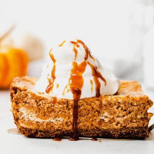Slice of pumpkin swirl cheesecake topped with whipped cream