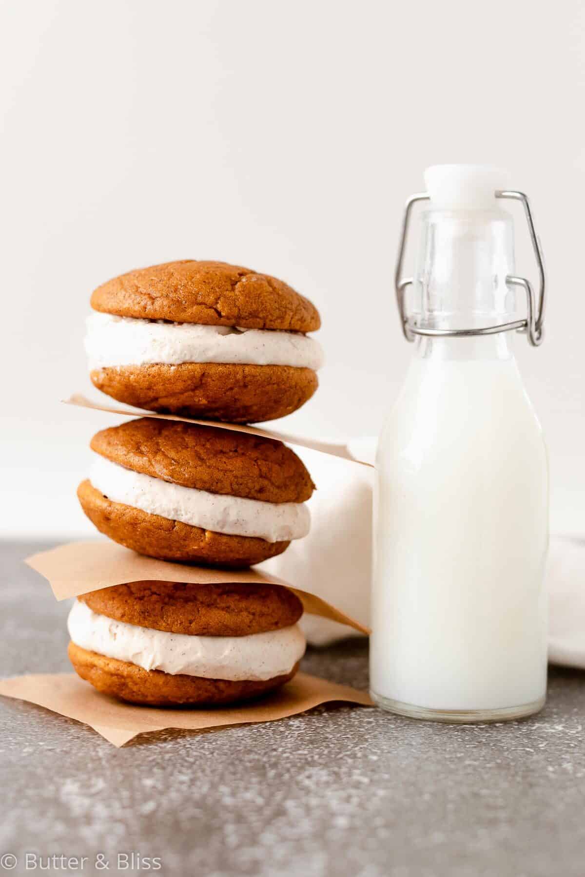 A stack of three pumpkin whoopie pies with cream cheese filling