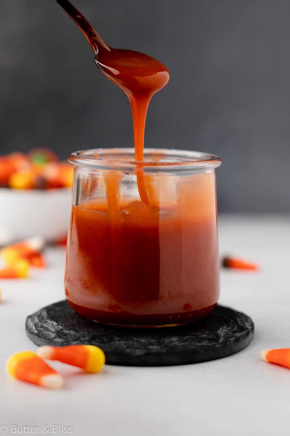 Candy corn caramel being drizzled into a jar