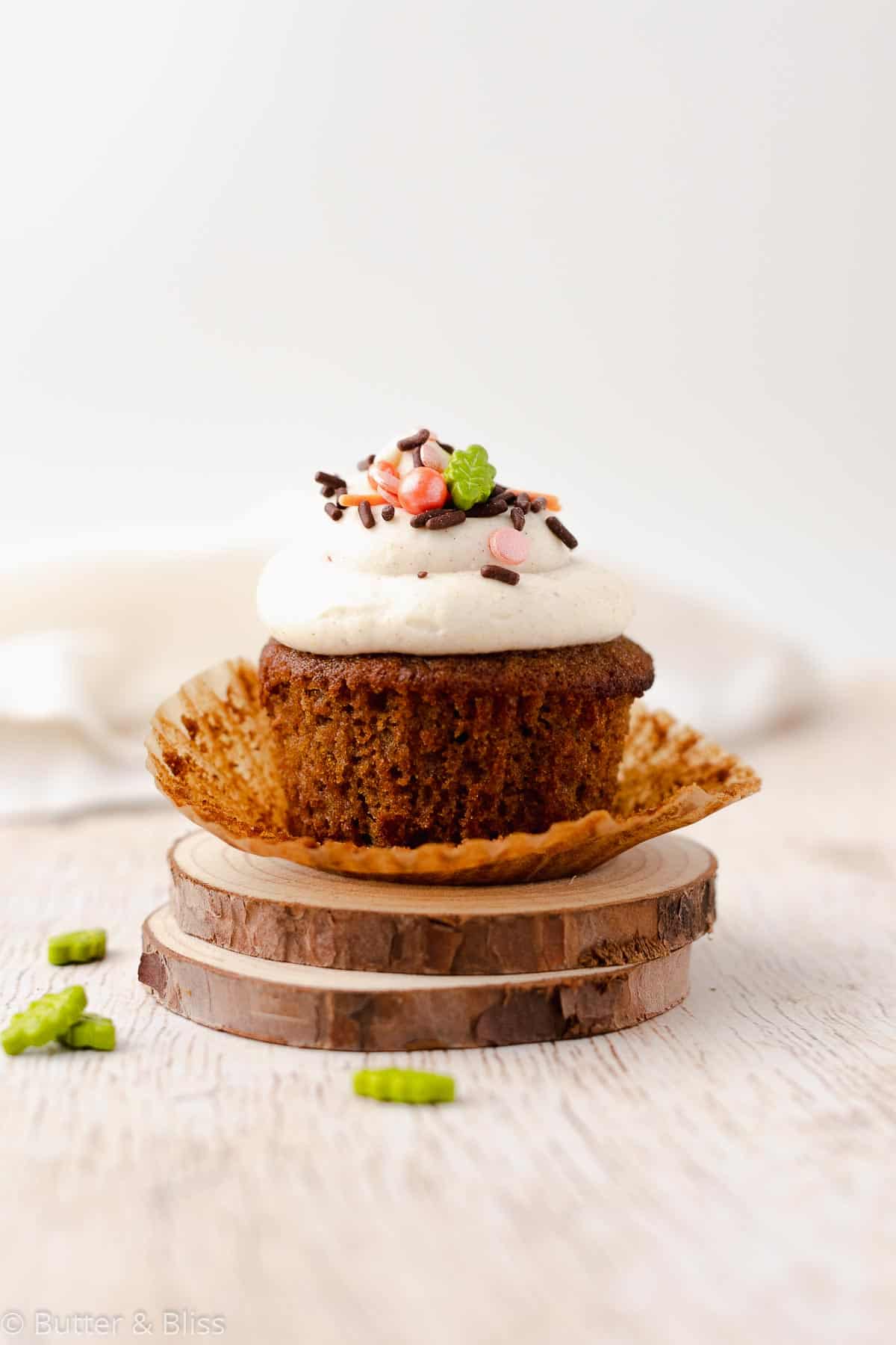 Single gluten free spice cupcake with frosting on a wooden plate