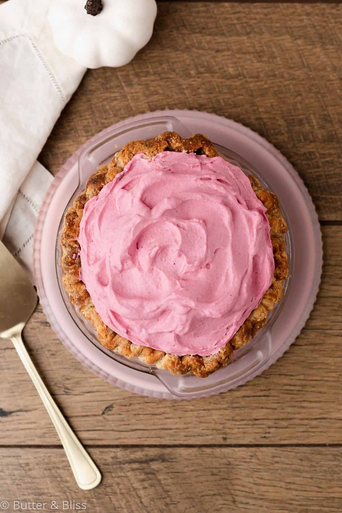 Top of a 6 inch pumpkin pie with cranberry whipped cream