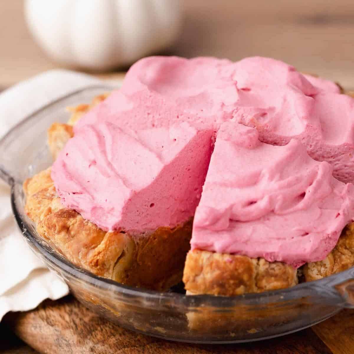 Mini pumpkin pie topped with cranberry whipped cream in a pie dish