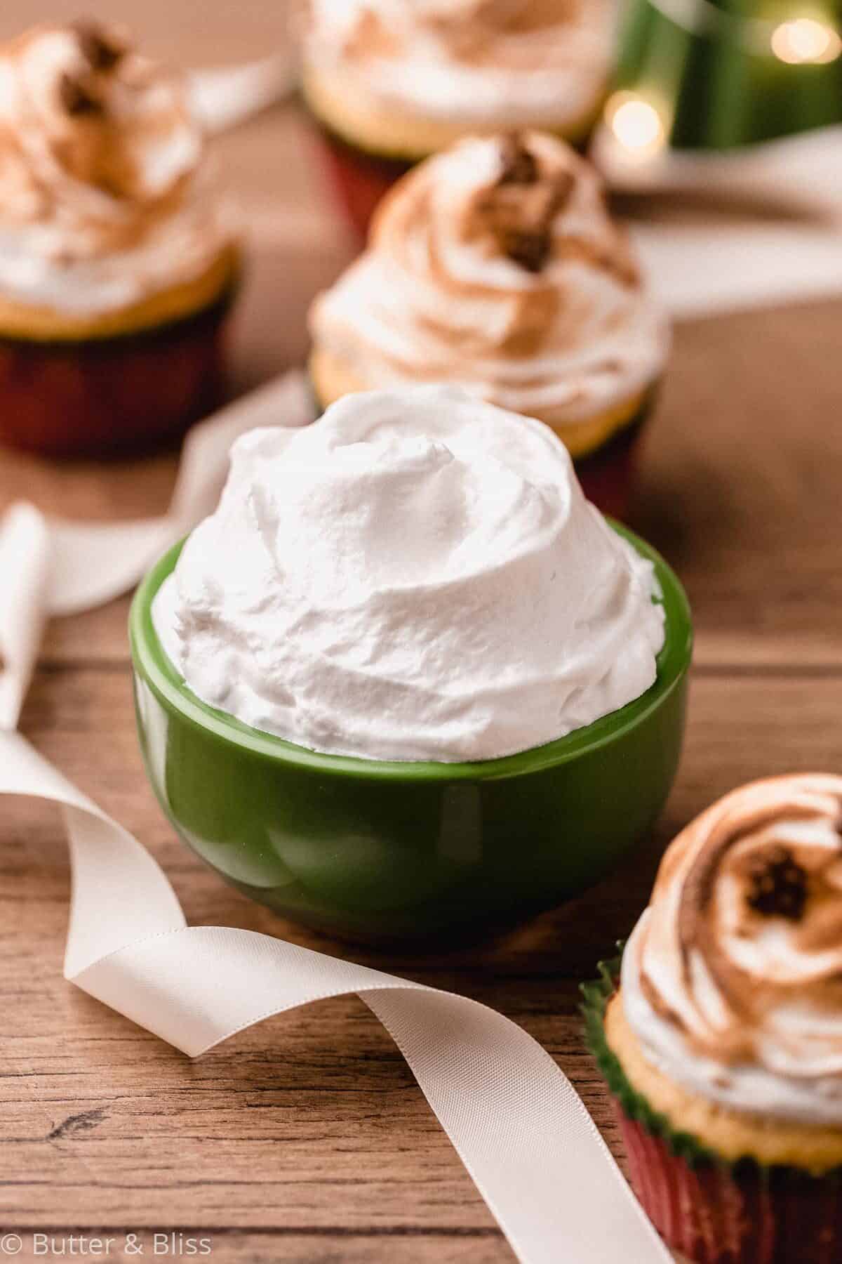 A bowl of marshmallow frosting set on a table.