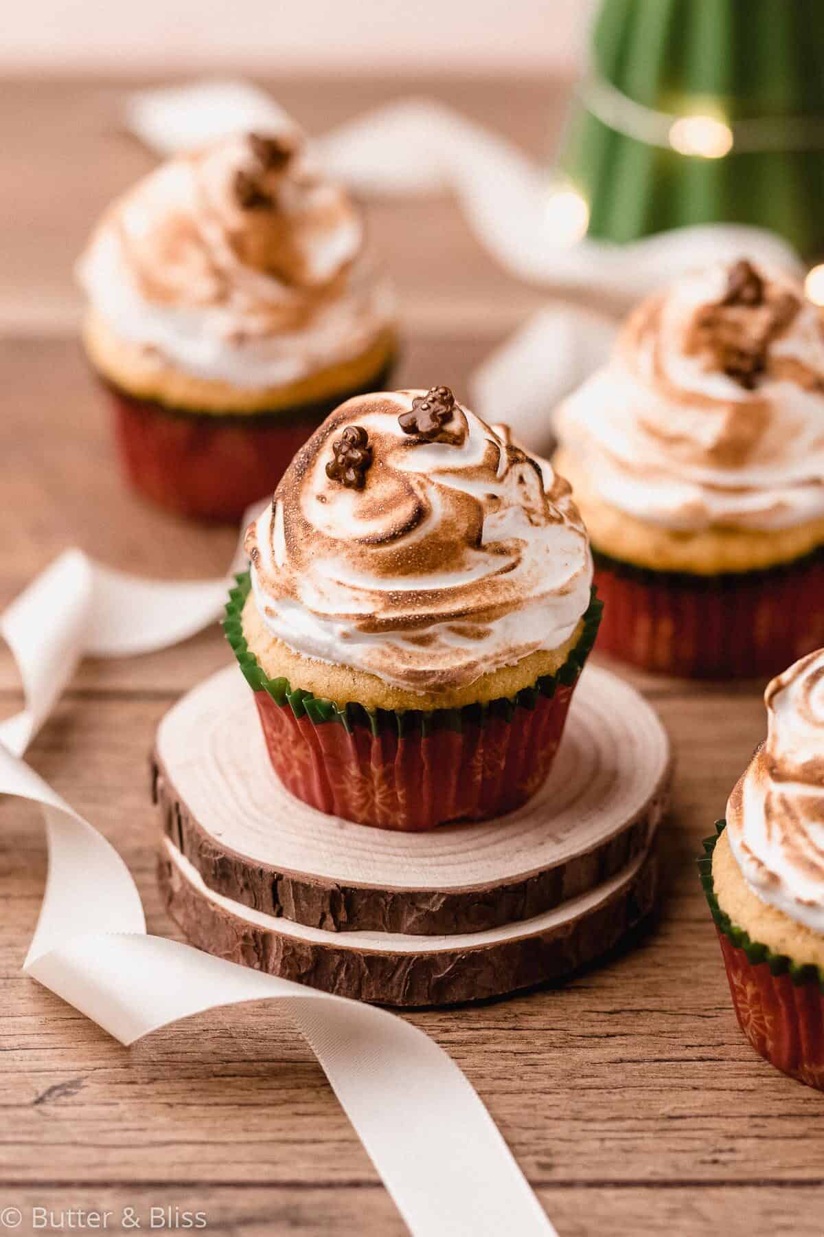 An eggnog cupcake with marshmallow frosting on mini wood coaster.
