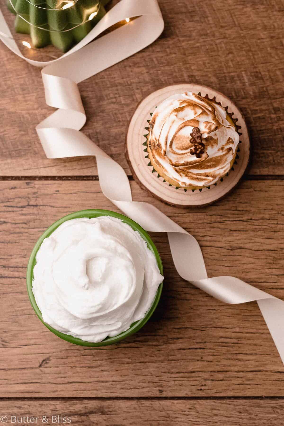 Frosting for a Christmas cupcake in a bowl next to a cupcake.