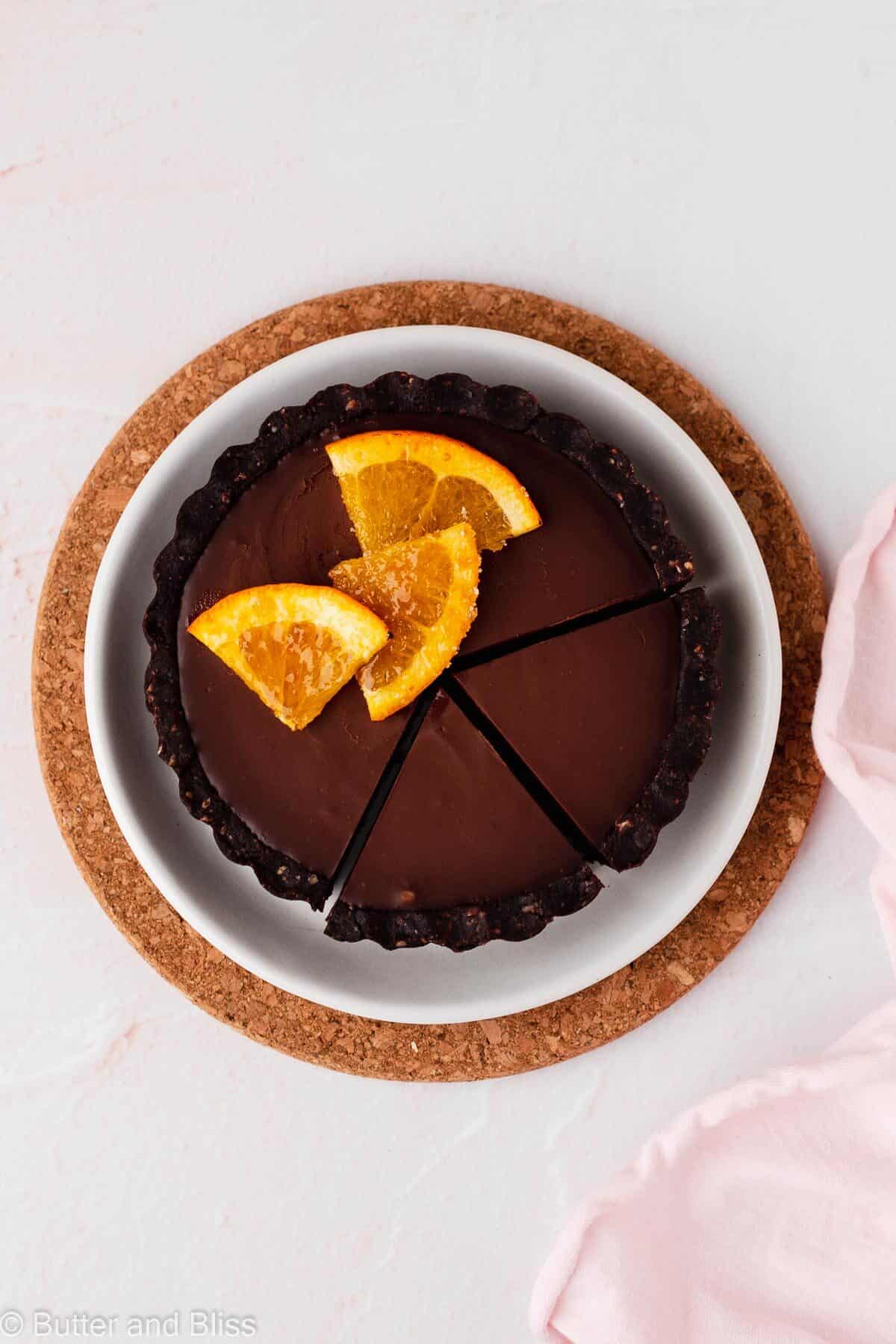 A mini gluten free chocolate orange tart with slices cut on a small plate.