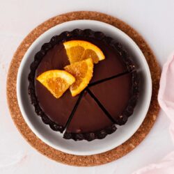 A mini gluten free chocolate orange tart with slices cut on a small plate