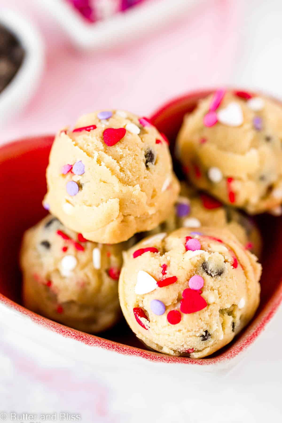 Heart shaped bowl of Valentine's Day edible chocolate chip cookie dough with heart sprinkles.