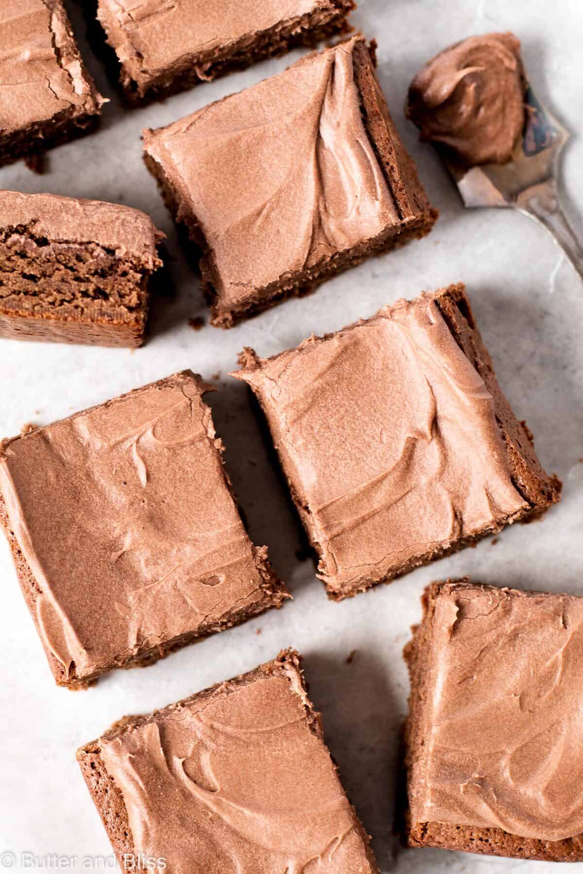 Frosted brownie blondies cut into squares on a piece of parchment paper