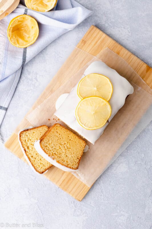 Top view of a gluten free iced lemon loaf sliced on a wood cutting board