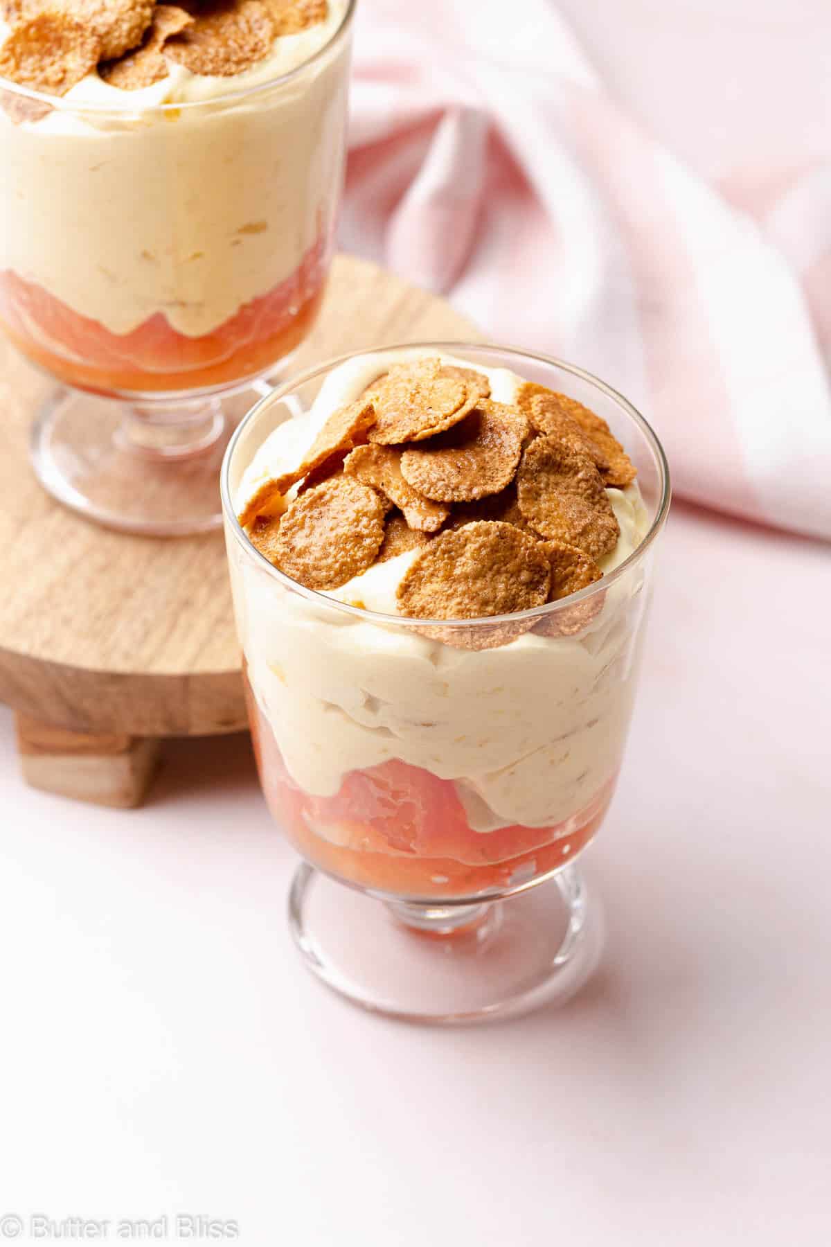 Top view of a parfait glass filled with mango grapefruit cream dessert topped with maple cornflakes