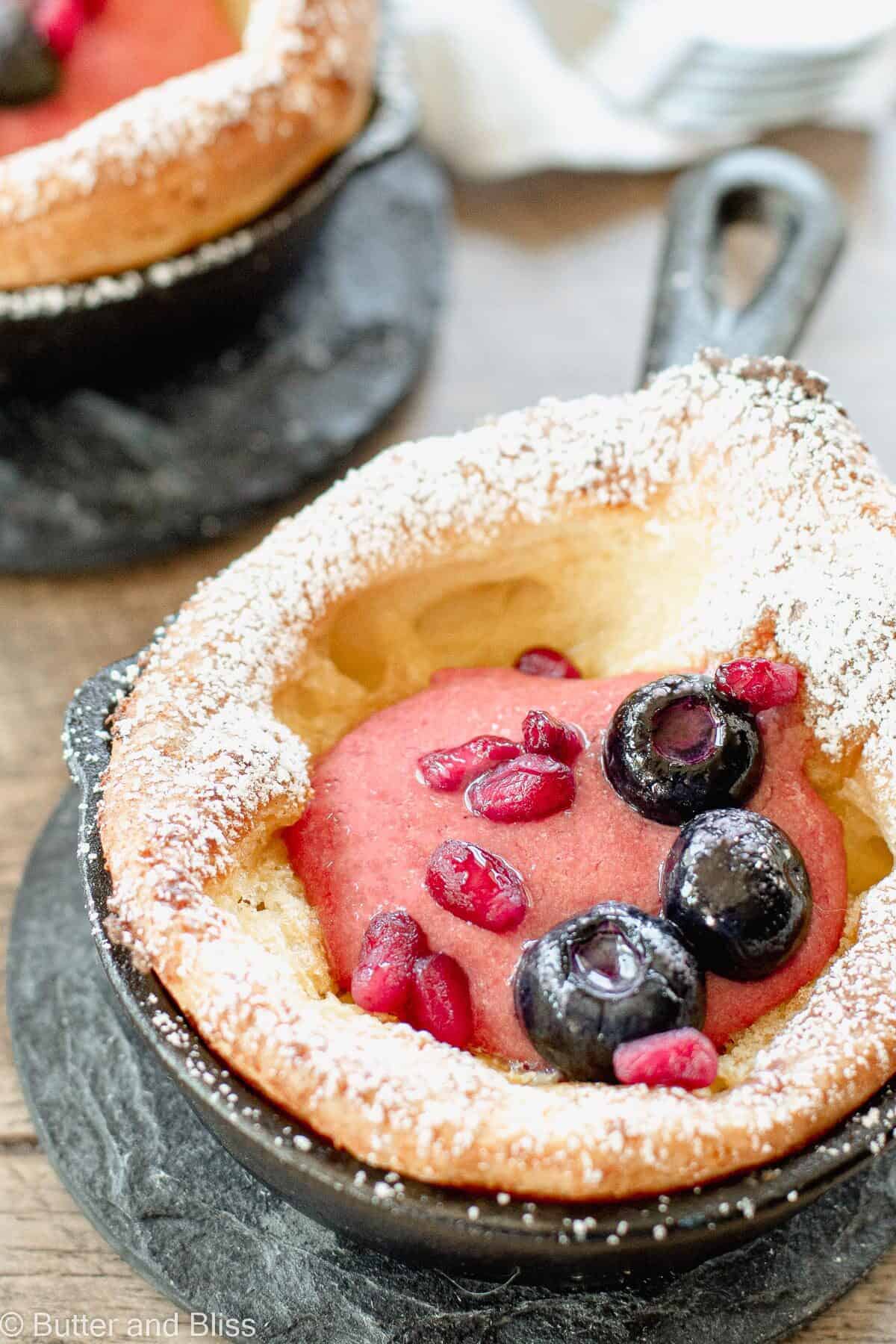Mini dutch baby pancake in a skillet filled with cherry cream