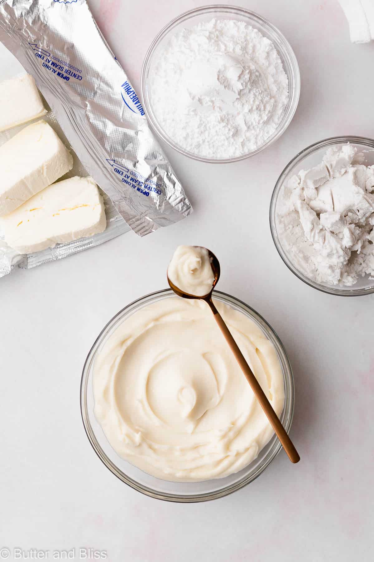 Cream cheese frosting in a bowl with ingredients around in