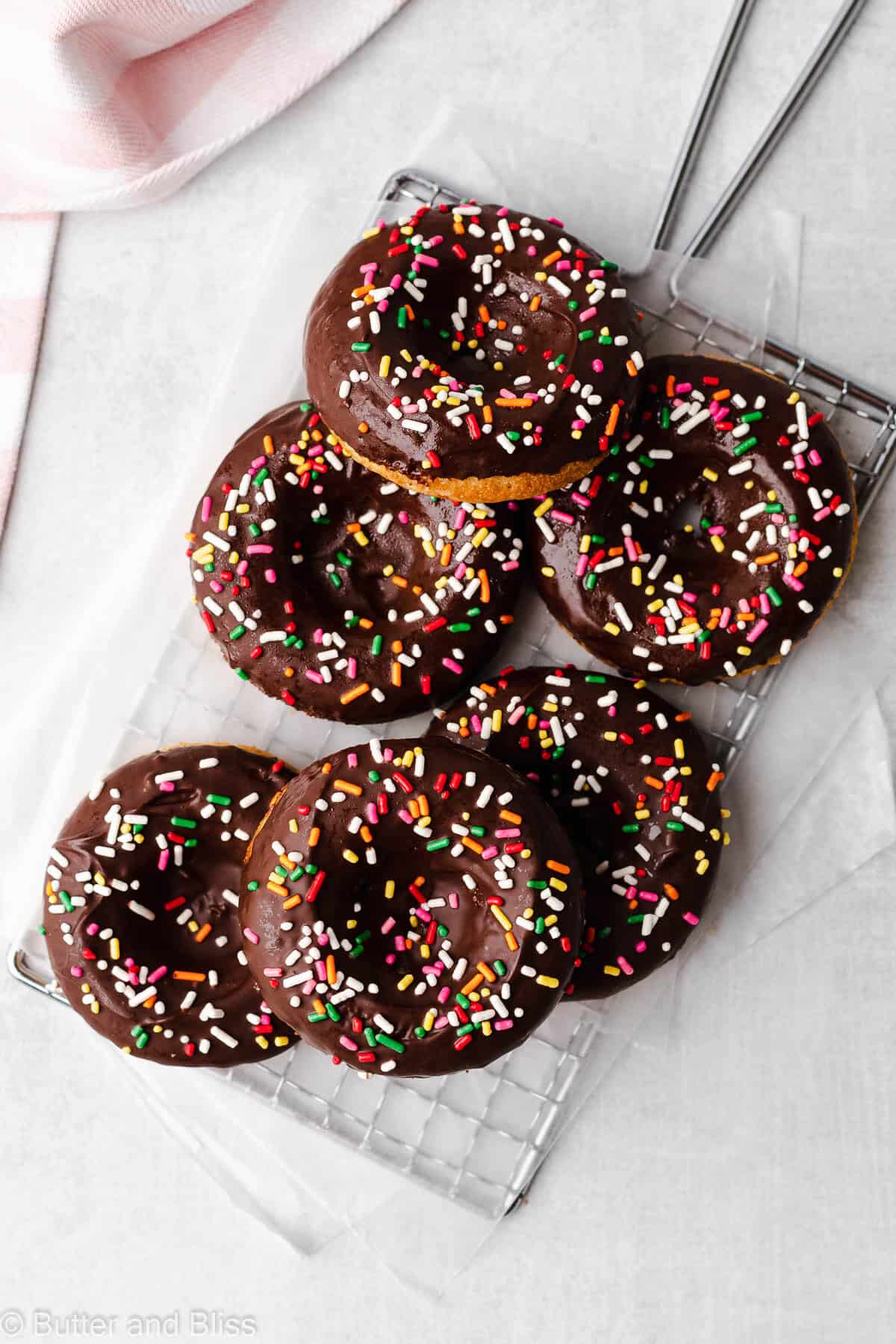 Chocolate glazed donuts with sprinkles in a pile on a wire cooling rack