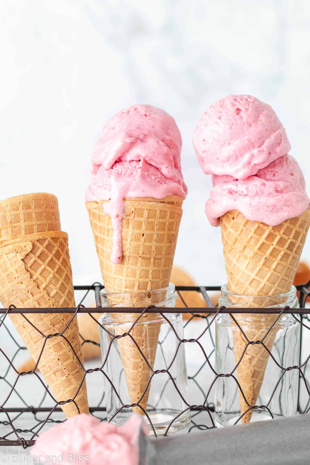 Dairy free strawberry ice cream scoops on two sugar cones
