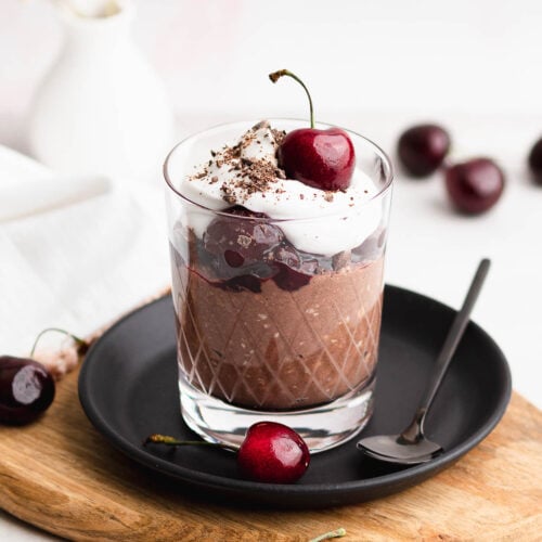 Black forest overnight oats in a glass on black plate
