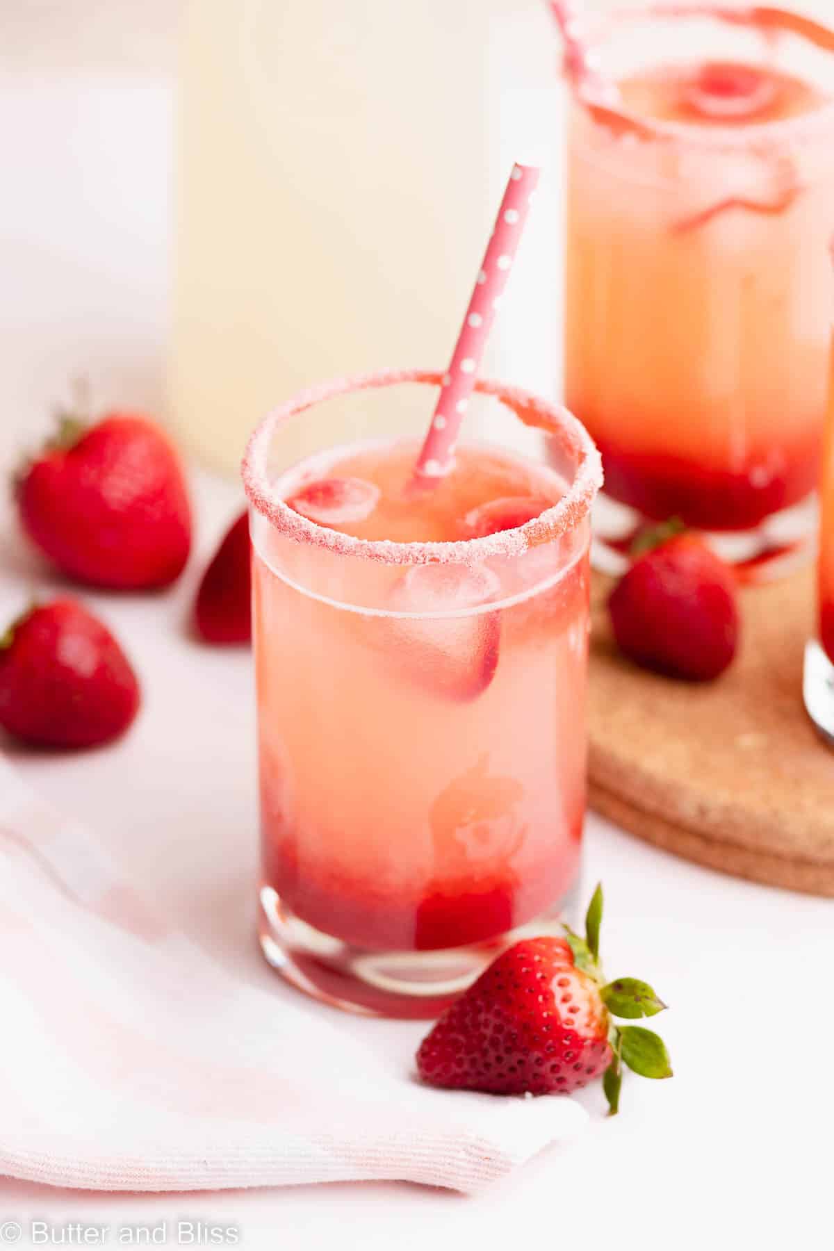 Close up of a glass of strawberry lemonade with a pink straw