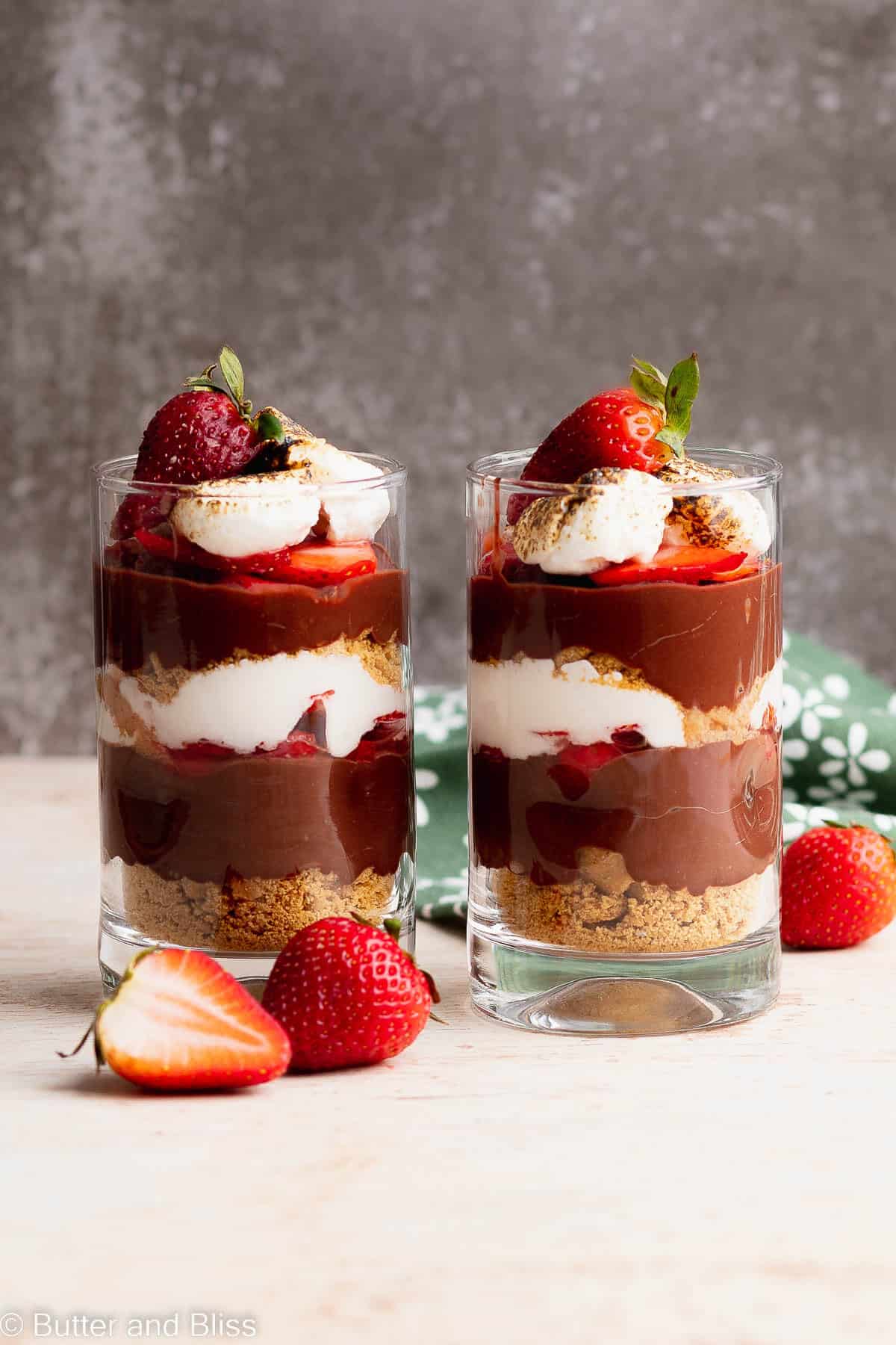 Two strawberry smores desserts in parfait glasses on a table