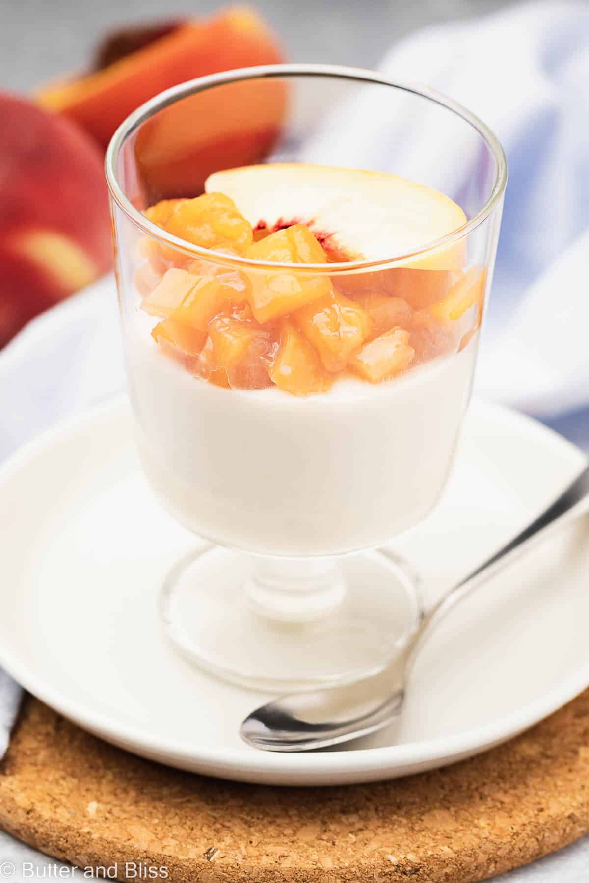 Close up of peach panna cotta topped with peach slices in a parfait glass