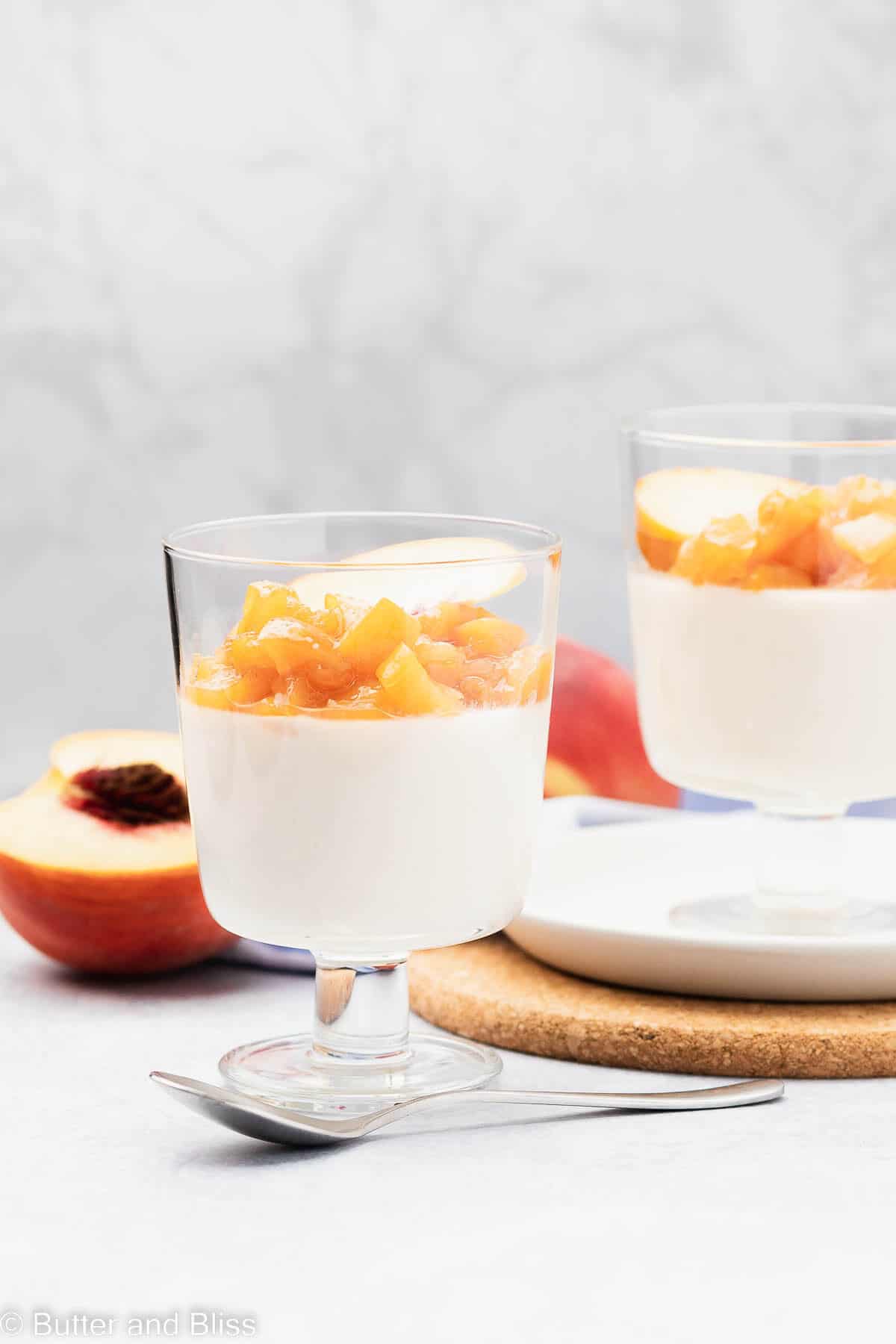 Two peach panna cotta parfait desserts on a table