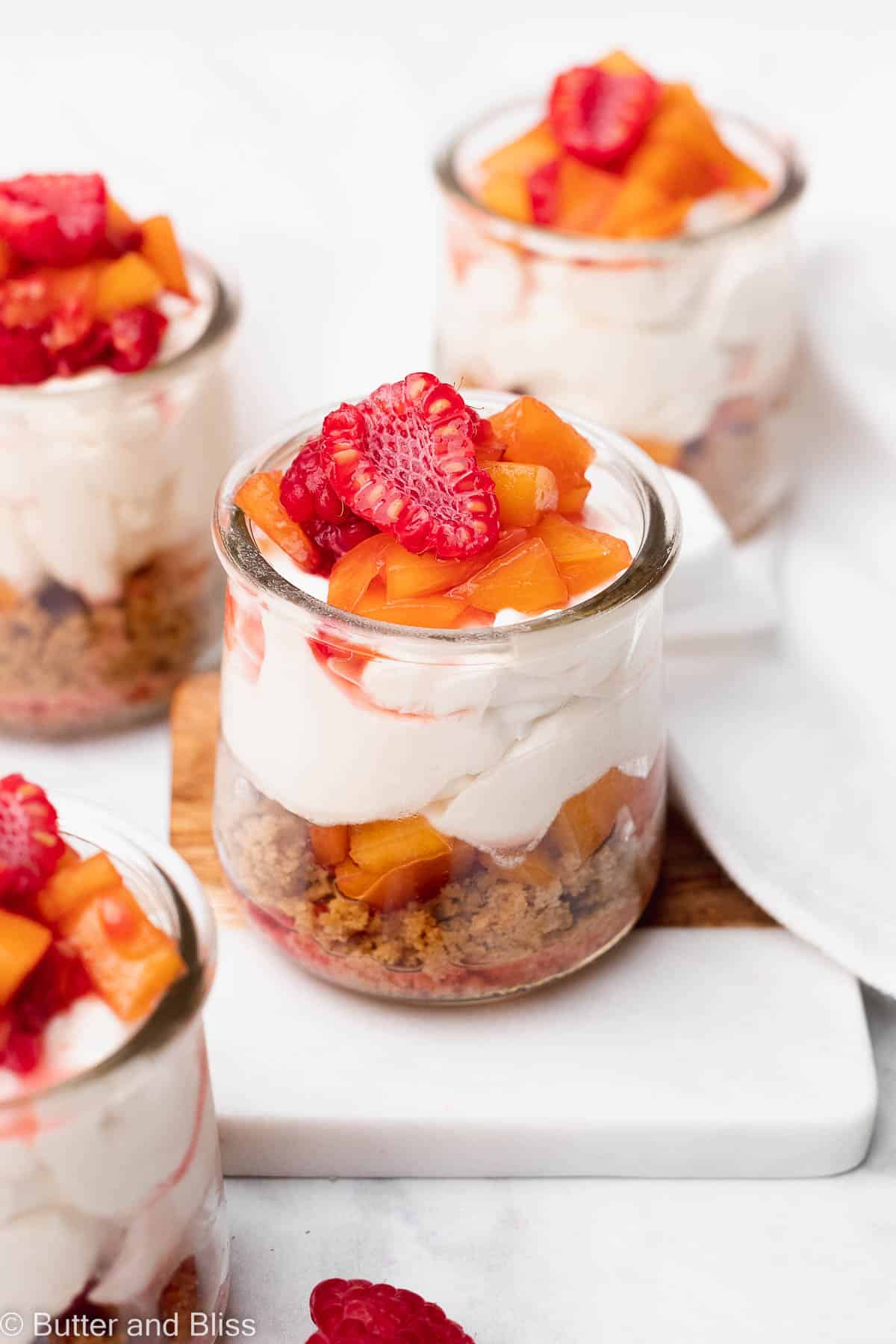 Pretty no bake cheesecake in layers in a small glass jar and topped with fresh fruit.