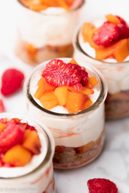 Close up of a deconstructed raspberry peach cheesecake in a small glass cup.