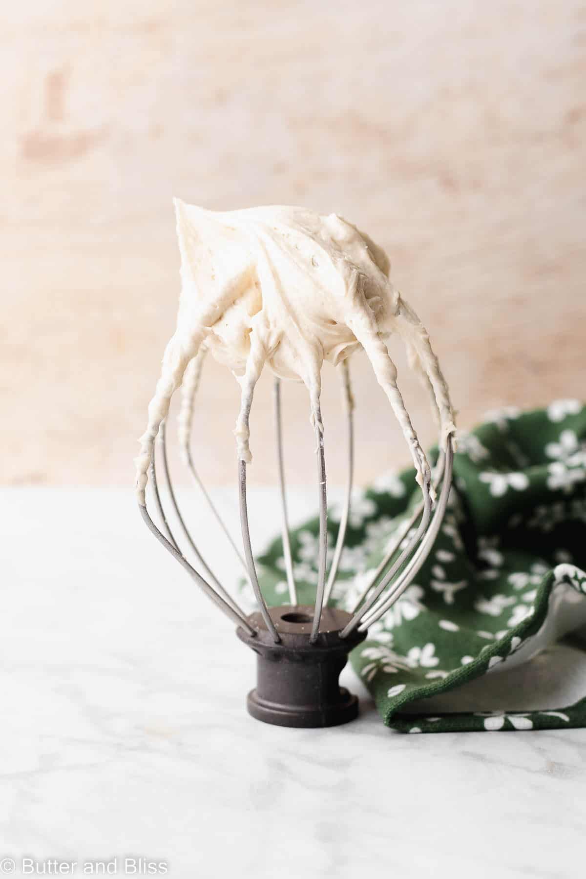 Fluffy caramel frosting made without butter on a whisk.